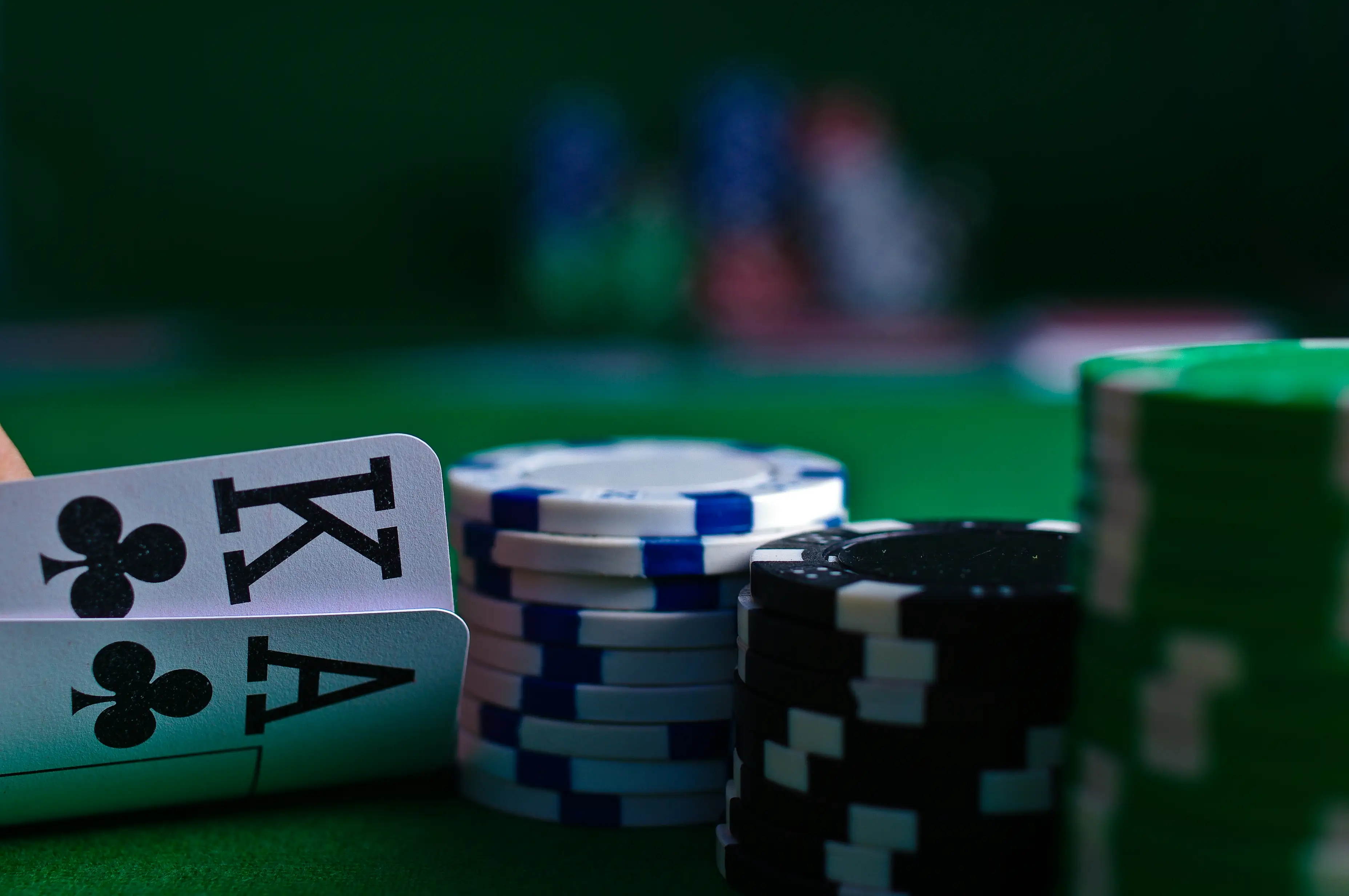 Pokerkort og fargerike sjetonger på grønt spillebord